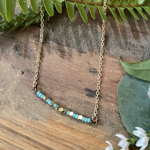 Matte turquoise and brass beaded small stream necklace on a 16-18" adjustable matte gold chain